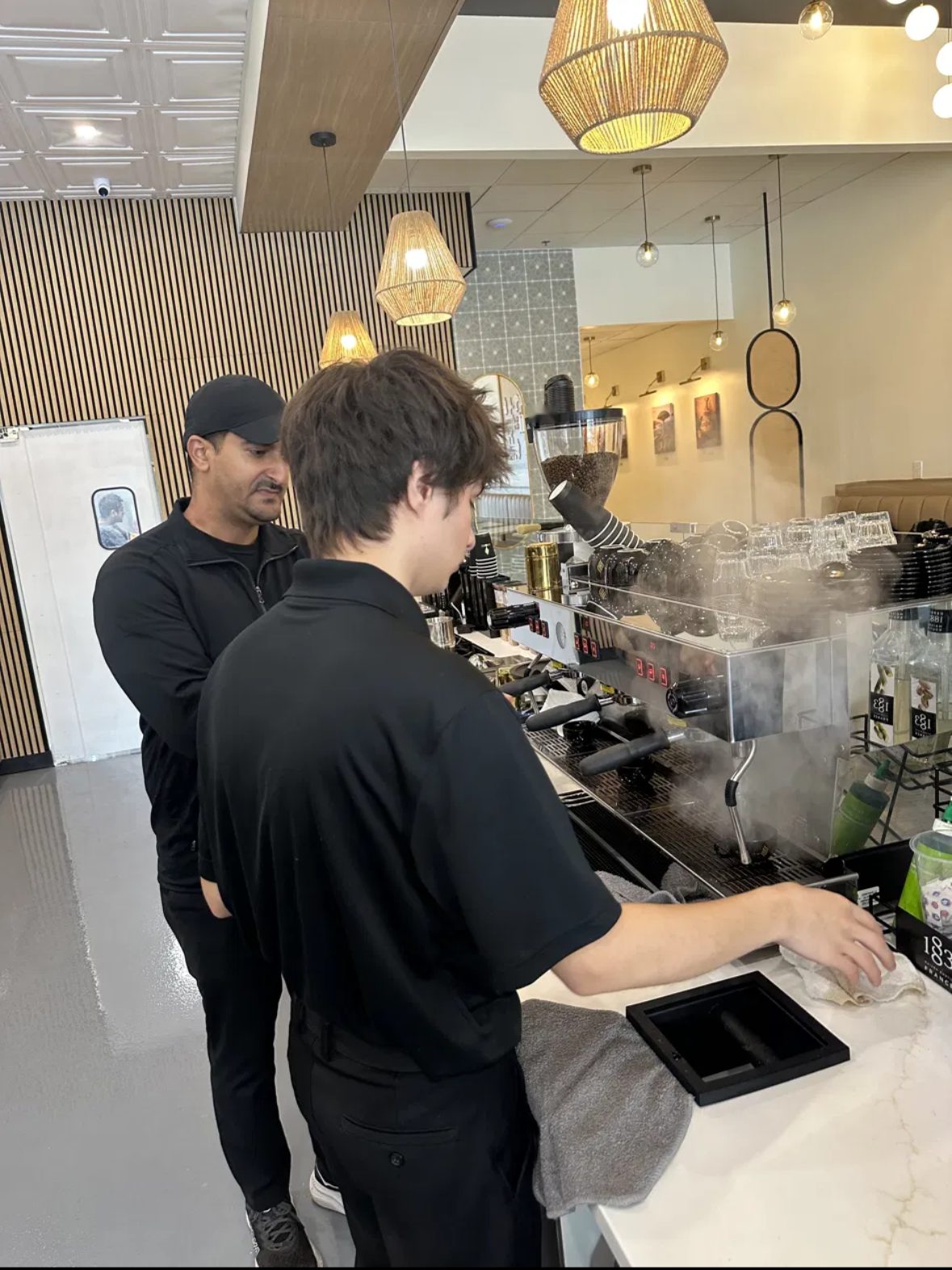 Deen coaching a barista at the espresso machine during training